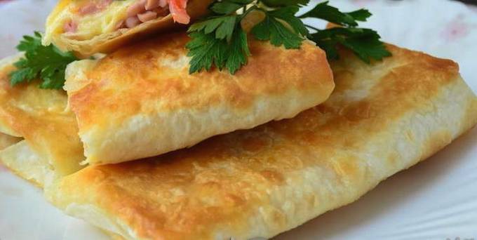 Lavash envelopes with sausage and cheese in a pan