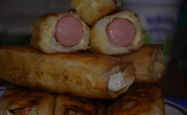 Sausages with potatoes and cheese in pita bread in a pan