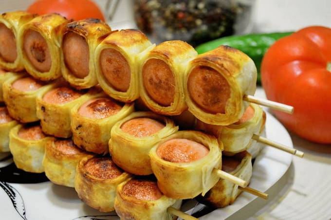 Sausages in pita bread on skewers in a pan
