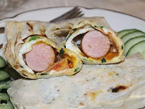 Sausages in pita bread with egg in a pan