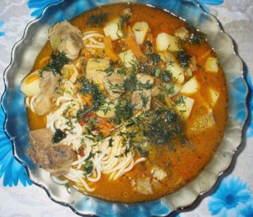 Pork lagman with potatoes and noodles in a classic cauldron