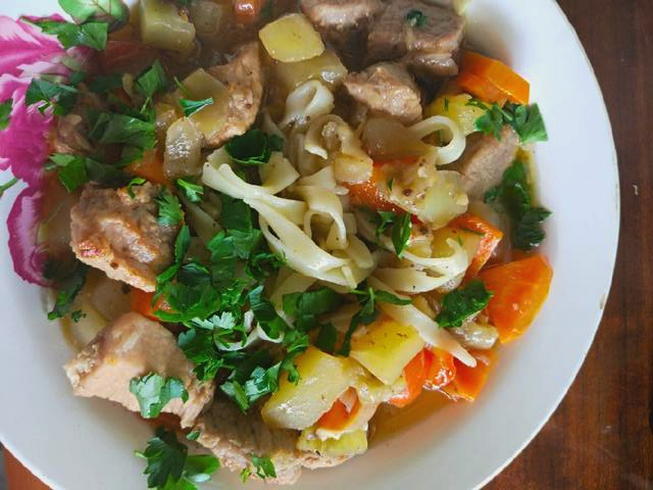 Pork lagman on a fire in a cauldron