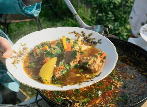 Beef lagman on a fire in a cauldron