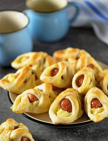 Sausages with potatoes in puff pastry in the oven