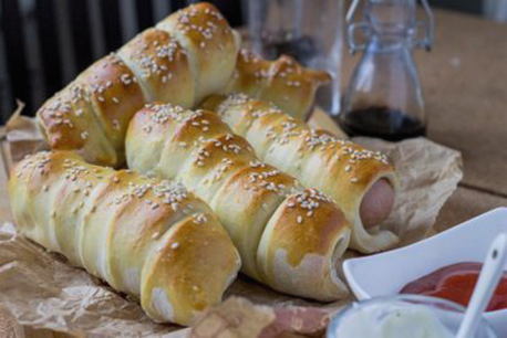 Sausages in puff yeast dough with sesame seeds in the oven