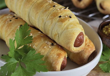 Sausages in puff pastry with sesame seeds in the oven