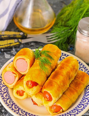 Sausages in puff yeast dough in a pan