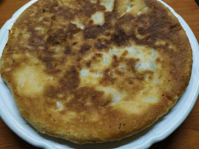 Ossetian flatbread with cheese and herbs in a pan