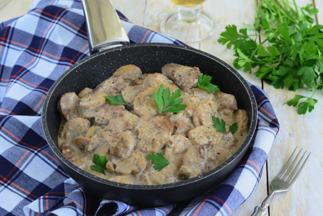 Chicken liver in sour cream with onions and mushrooms in a pan