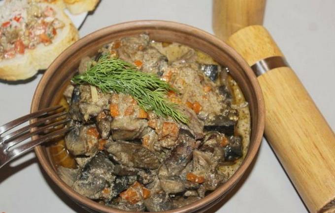 Chicken liver with mushrooms in sour cream in a pan