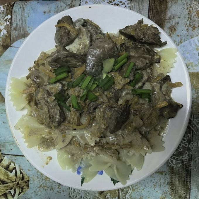 Chicken liver in mayonnaise with onions and carrots in a pan