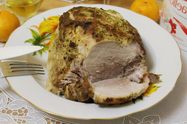 Whole piece of pork with mustard in foil in the oven