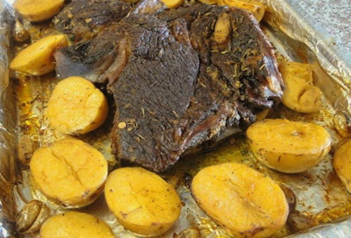 A piece of beef with potatoes baked in foil in the oven