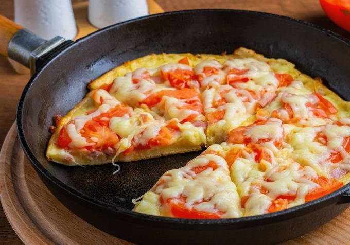 Pizza with sausage, tomatoes and cheese in a pan