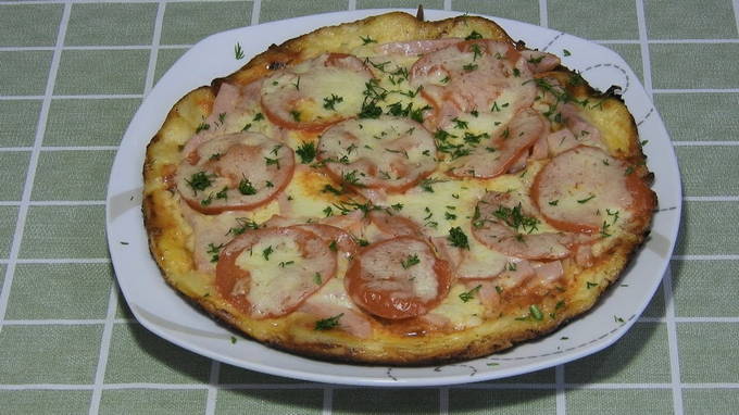 Pizza with sausages, tomatoes and cheese in a pan